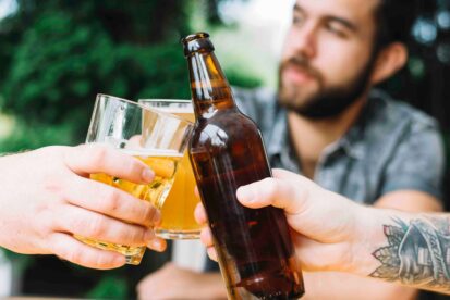 Drei Maenner stossen mit Bier an