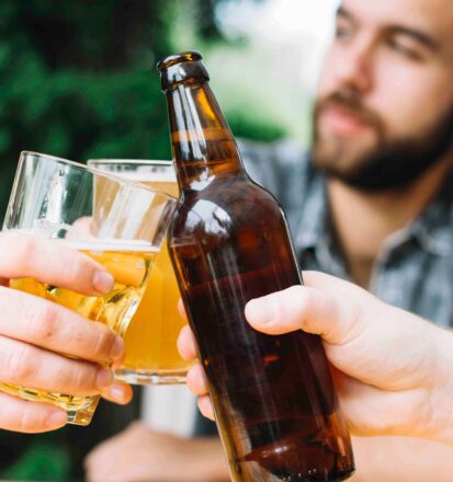 Drei Maenner stossen mit Bier an