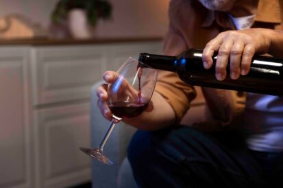Ein alter Mann schenkt sich ein Glas Rotwein ein