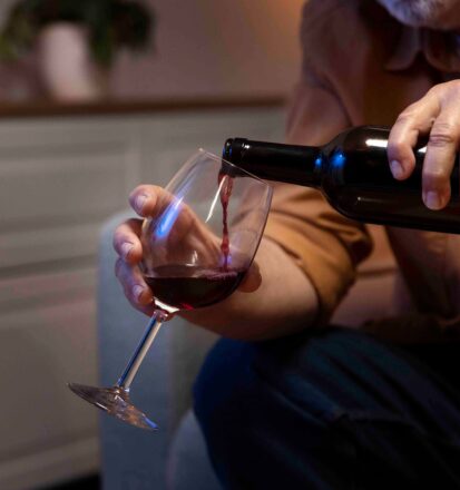 Ein alter Mann schenkt sich ein Glas Rotwein ein