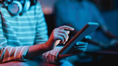 Frau mit Kopfhoerern bedient Tablet