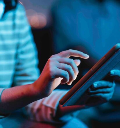 Frau mit Kopfhoerern bedient Tablet