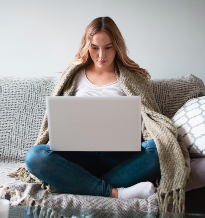 Junge Frau sitzt am Laptop und findet die Online-Beratung der Paritaetischen Suchthilfe Niedersachsen