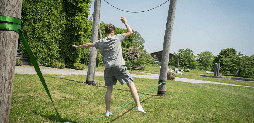 Junger Mann turnt auf einer Slackline in der Klinik am Kronsberg
