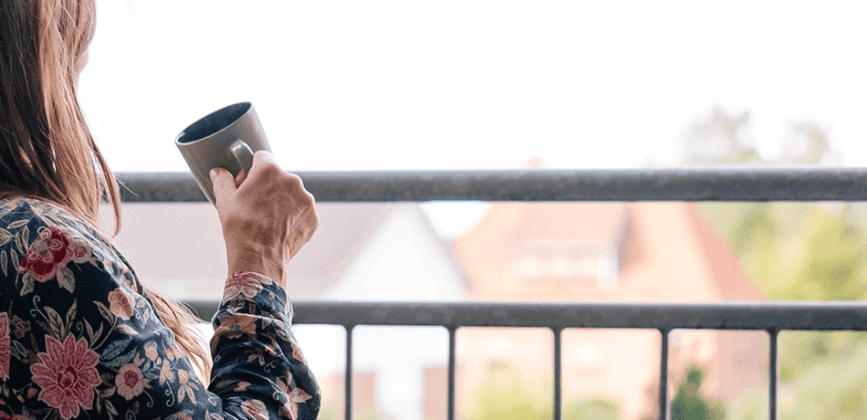 Frau trinkt Kaffee auf einem Balkon im Haus Hliuni